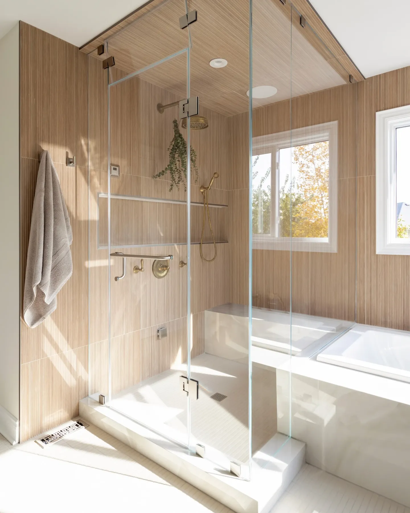 Glass walk-in shower with vertical wood-look tile and brass fixtures