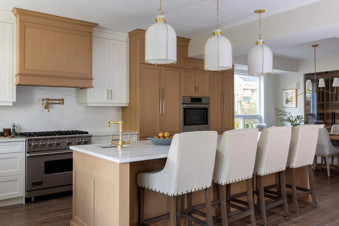White oak kitchen island with upholstered counter stools and globe pendant lights